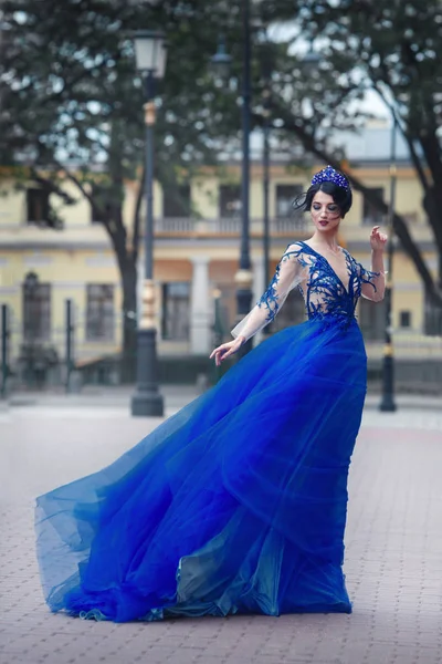 美丽的黑发女人与蓝色皇冠蕾丝礼服摆姿势在城市街道上 — 图库照片