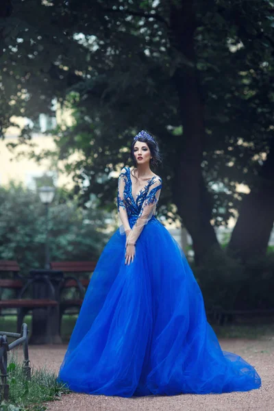 美丽的黑发女人与蓝色的皇冠蕾丝礼服站在公园 — 图库照片