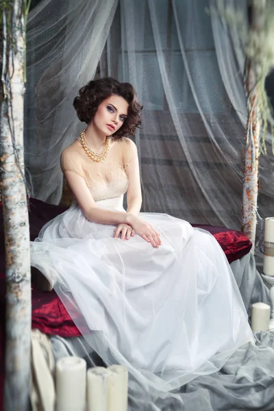 Mooie Bruid Met Elegante Kapsel Witte Trouwjurk Zittend Bed Studio — Stockfoto