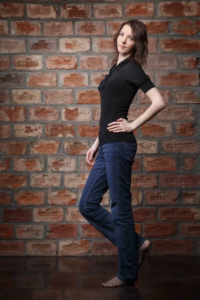 young woman in casual clothes posing on brick wall background