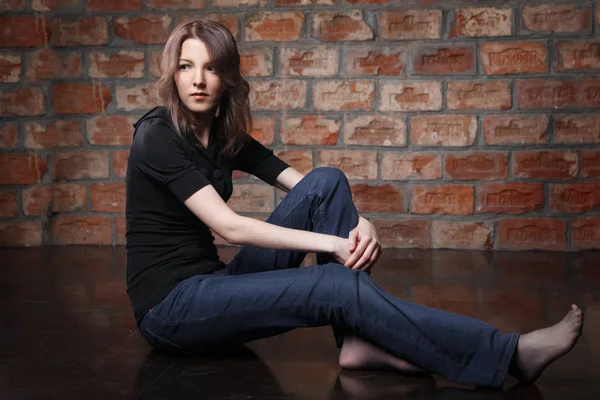 young woman in casual clothes posing on brick wall background