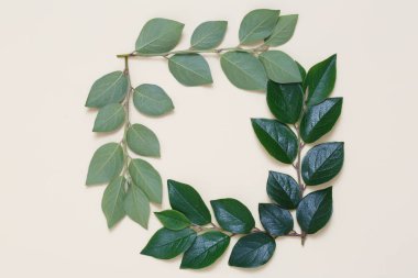 Bej renkli arka plan üzerinde yapraklarla kaplı bir yaratıcı bir üstten görünüm karedir.