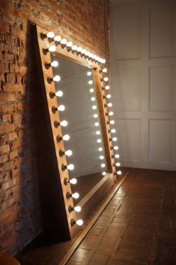 Çatı katında ışık lı bir çerçevede büyük bir ayna duruyor.