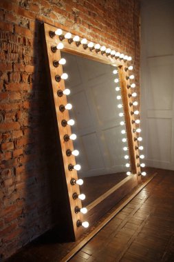 Çatı katında ışık lı bir çerçevede büyük bir ayna duruyor.