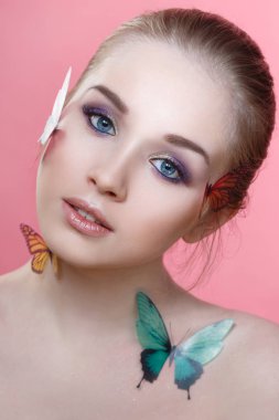 Yüzünde pembe bir arka plan üzerinde izole yüzünde nazik bir makyaj ve kelebekler ile güzel bir kız Güzellik moda portre.