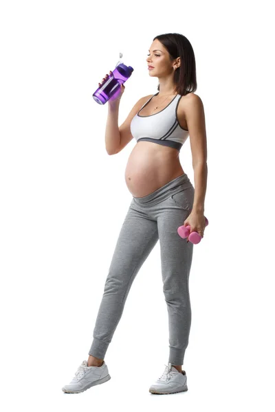 苗条的运动怀孕的女孩站在一瓶水和哑铃在手隔离在白色背景 — 图库照片