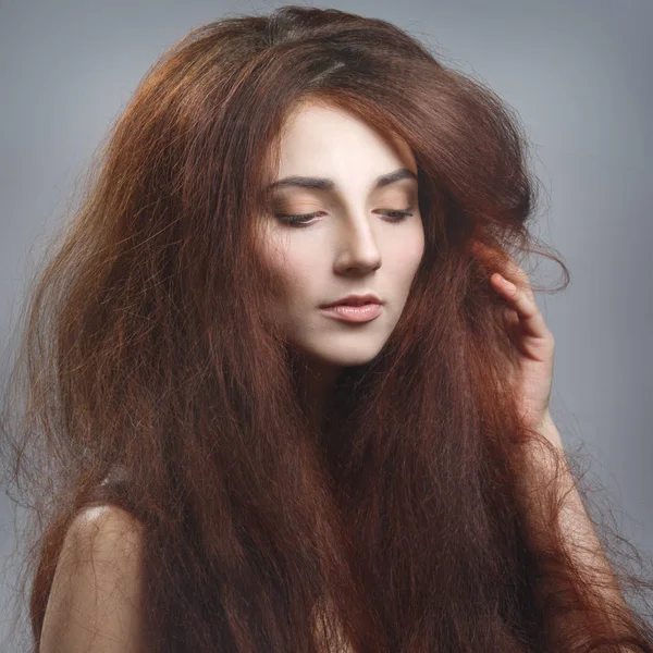 Beauty portrait of an elegant girl with beautiful long hair isolated against a gray background.