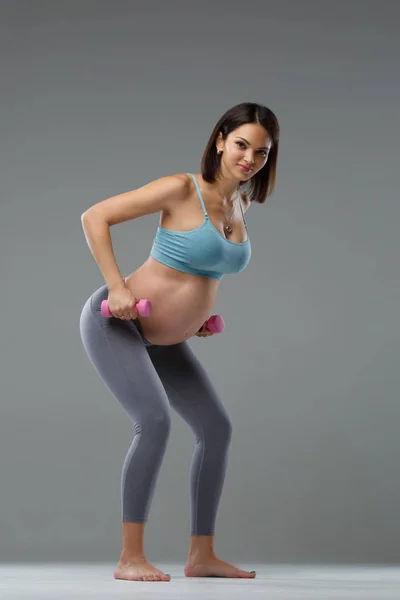 Szczupła Kobieta Ciąży Jest Zaangażowany Fitness Izolowane Szarym Tle — Zdjęcie stockowe