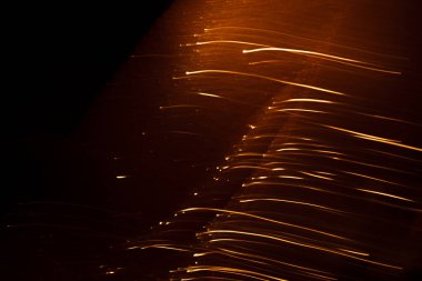 Koyu arkaplandaki kıvılcımlardan gelen soyut turuncu çizgiler.