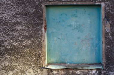 Kalıplı alçı duvarda turkuaz boyayla boyanmış kör bir pencere..