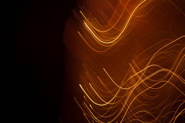 Koyu arkaplandaki kıvılcımlardan gelen soyut turuncu çizgiler.