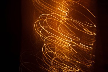 Koyu arkaplandaki kıvılcımlardan gelen soyut turuncu çizgiler.