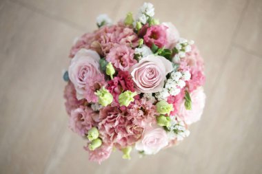 Çiçeklerin pembe tonlarında zarif bir düğün buketi..