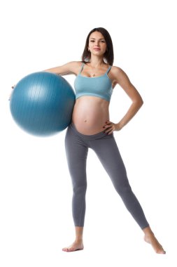 Sıska hamile kadın, beyaz arka planda izole edilmiş bir topla fitness yapıyor..