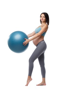 Sıska hamile kadın, beyaz arka planda izole edilmiş bir topla fitness yapıyor..