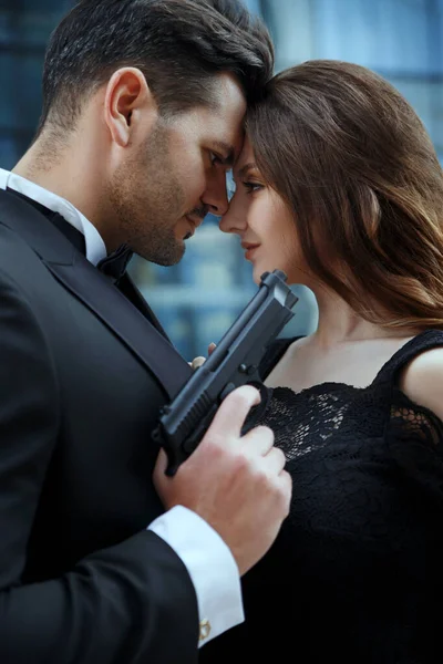 Portrait of an elegant man with guns in hands of a beautiful girl.