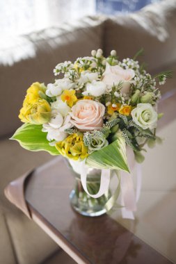 Bahar çiçeklerinden oluşan parlak bir buket, bir restoranın masasındaki cam vazoda..