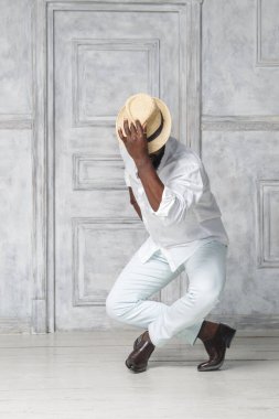 Beyaz takım elbiseli siyah bir adam dans ediyor..