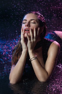 Tutkulu seksi kızın güzel portresi. Karanlık bir arka planda su damlalarında..