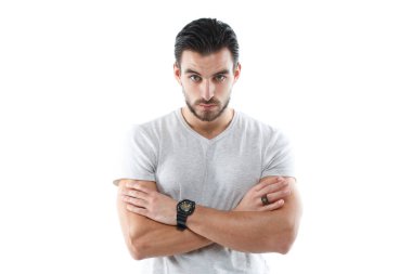 Hafif dar tişörtlü, karizmatik genç bir atletik kolları göğsünün üzerinde beyaz bir arka planda izole bir şekilde duruyor..