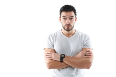 Hafif dar tişörtlü, karizmatik genç bir atletik kolları göğsünün üzerinde beyaz bir arka planda izole bir şekilde duruyor..