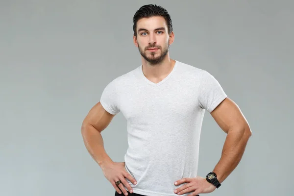 Attractive athletic man in a white shirt isolated on gray background.