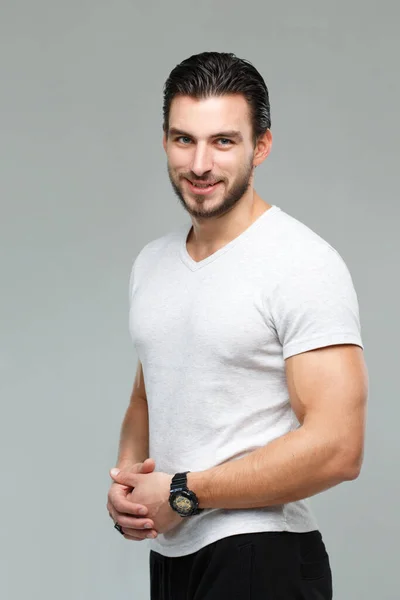 Attractive athletic man in a white shirt isolated on gray background.