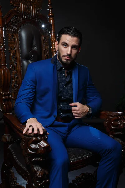 고전적 파란색 양복을 어두운 배경을 배경으로 의자에 품위있는 — 스톡 사진