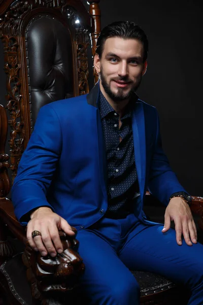 고전적 파란색 양복을 어두운 배경을 배경으로 의자에 품위있는 — 스톡 사진