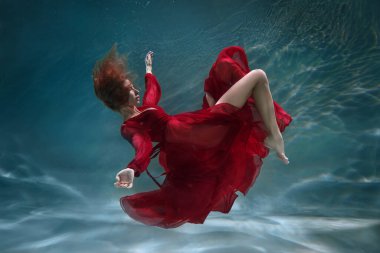Suyun altında uzun kırmızı elbisesi olan ince, güzel bir kız..