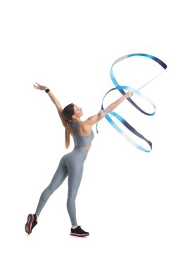 Spor kıyafetleri içinde ince bir jimnastikçi kız, beyaz arka planda izole edilmiş mavi kurdeleli, gri bir performans sergiliyor..