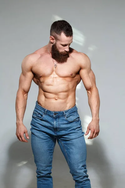体格健壮 留着胡子 全身肌肉赤裸 穿着蓝色牛仔裤 灰色背景的男人 — 图库照片