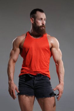Kırmızılı kaslı sakallı adam gri arka planda izole edilmiş..