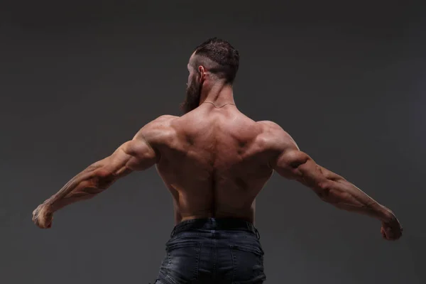 黒い灰色の背景に筋肉を示す裸体の胴を持つ運動選手の肖像 背中からの眺め — ストック写真