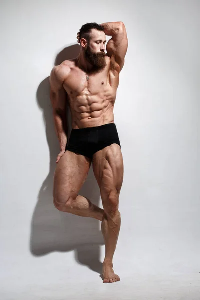 アスレチック製の髭の男は 軽い背景で完全に成長している筋肉を示しています — ストック写真