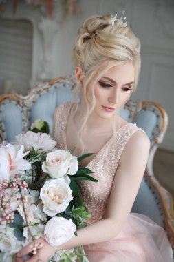 Zarif bir sarışın gelinin zarif portresi elinde bir buket çiçekle iç kısımda açık pembe bir elbise..