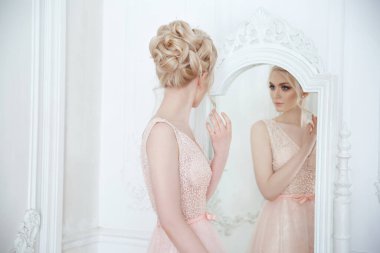 Zarif bir düğün saç stili olan güzel bir gelinin aynanın önünde nazikçe portresi.