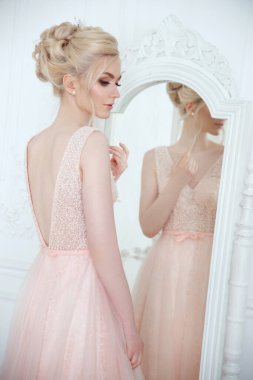 Zarif bir düğün saç stili olan güzel bir gelinin aynanın önünde nazikçe portresi.