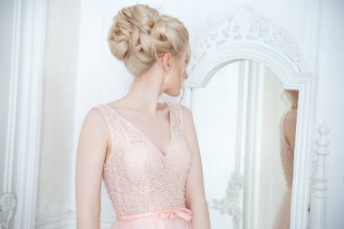 Zarif bir düğün saç stili olan güzel bir gelinin aynanın önünde nazikçe portresi.