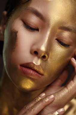 Güzel Asyalı bir kızın güzel portresi. Yüzünde altın rengi boya var..