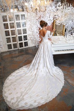 Şık elbiseli şık bir gelin. Arkasından uzun bir tren manzarası var..