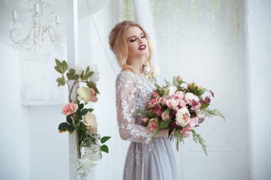 Ellerinde çiçek demetleriyle zarif saç stilleriyle bir gelin..