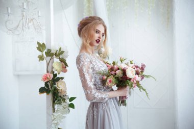 Ellerinde çiçek demetleriyle zarif saç stilleriyle bir gelin..