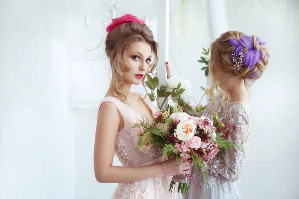 Two bride girls with hairdos with colored strands holding bouquets of flowers in their hands.