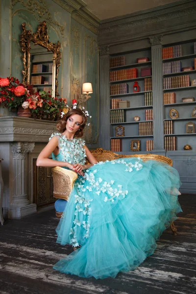Piękna Dziewczyna Bujnej Długiej Turkusowej Sukience Siedzi Krześle Eleganckim Wnętrzu — Zdjęcie stockowe