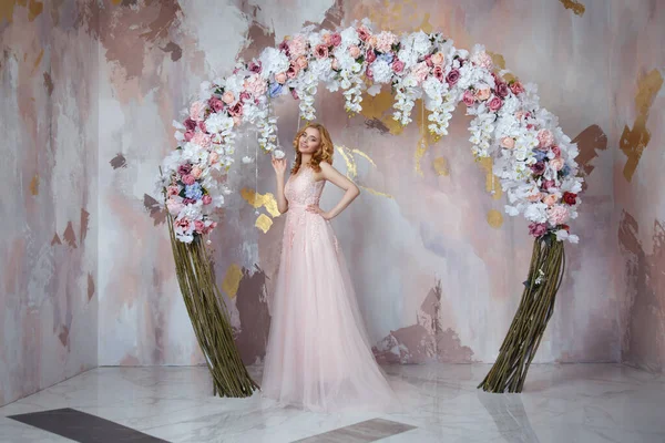 优雅的新娘 穿着长长的轻飘飘的粉色衣服 在花朵拱下 — 图库照片