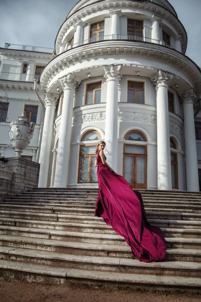 美丽纤细的姑娘 身穿深红色的丝质连衣裙 在皇宫的台阶上坐着一列长列火车 — 图库照片
