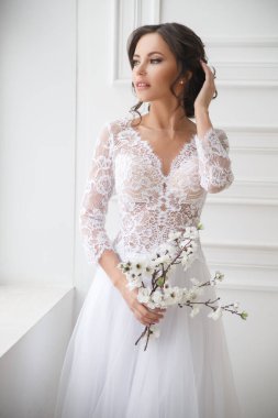 Güzel, zarif bir gelinin portresi Parlak bir iç mekânda bir buket sakura ile.