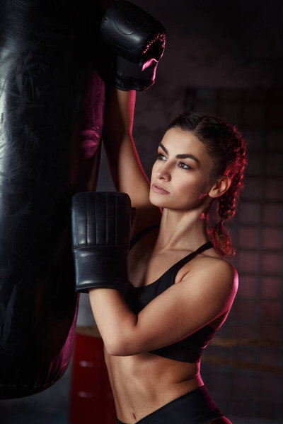 Beautiful slim sexy sportswoman in the ring and the gym in boxing gloves.