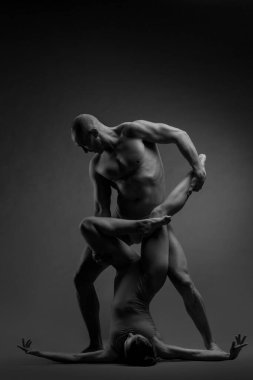 Siyah-beyaz bir çift dansçının zarif bir akrobatik poz içinde koyu bir arka planda çekilmiş bir fotoğrafı..